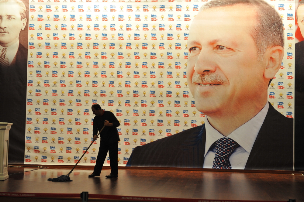 A janitor cleans the floor on a stage, waiting for Turkish President Recep Tayyip Erdogan - © thomas koch/Shutterstock