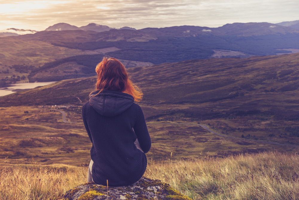 Donna seduta su una montagna in contemplazione © Lolostock/Shutterstock