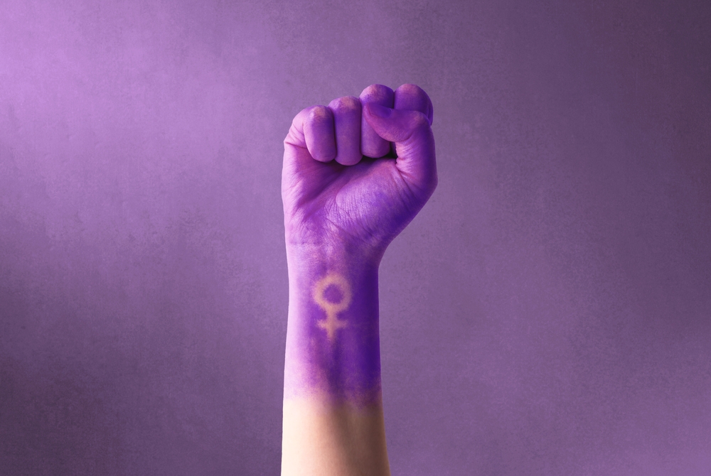 Pugno viola alzato di una donna per la giornata internazionale della donna e il movimento femminista © AdriaVidal/Shutterstock Pugno viola alzato di una donna per la giornata internazionale della donna e il movimento femminista © AdriaVidal/Shutterstock