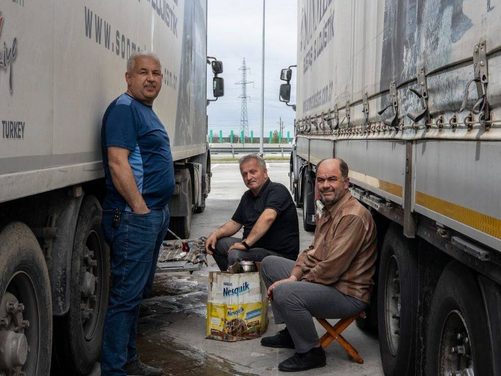 un gruppo di camionisti turchi si riposa all'ombra dei loro camion 