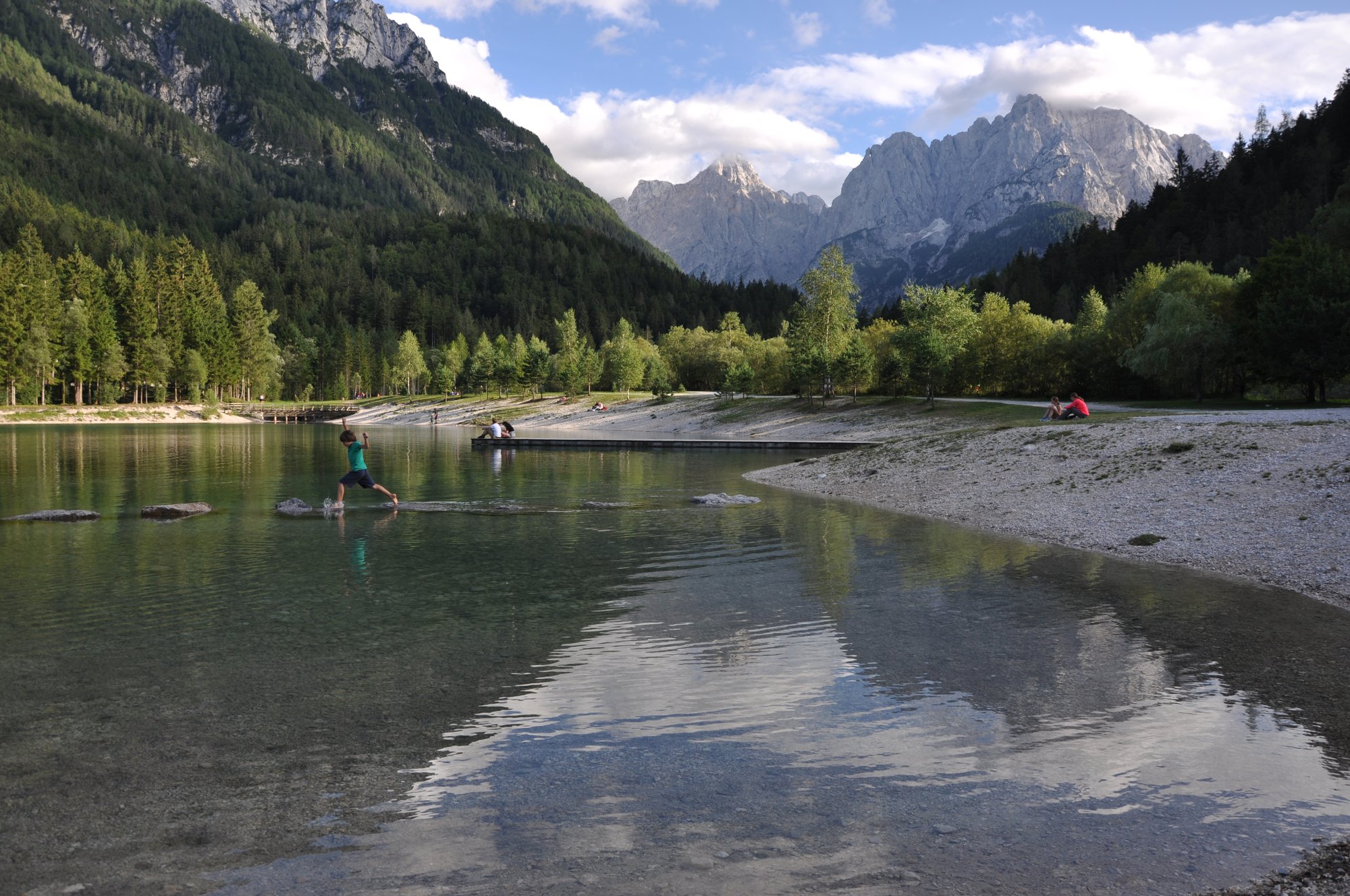 Bimbo salta da un sasso all'altro nel lago Jasna a Kranjska Gora 