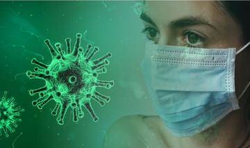 Rappresentazione del virus responsabile del COVID19 insieme ad una persona che indossa la mascherina protettiva