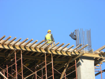 Un muratore su una struttura in cemento armato in costruzione