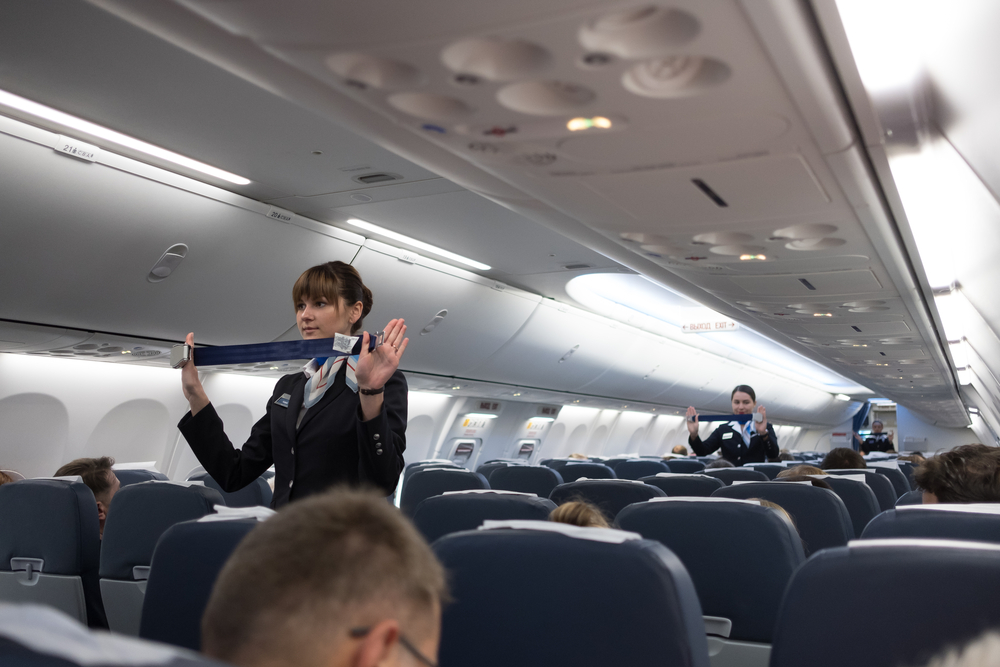 A bordo di un aereo le hostess indicano le misure di sicurezza © Akimov Igor/Shutterstock