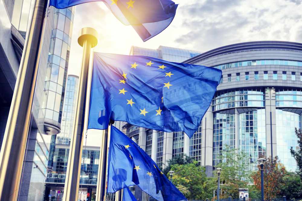 Bandiere dell'UE che sventolano davanti all'edificio del Parlamento europeo © symbiot/Shutterstock