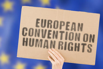 Una mano regge un cartello dedicato alla Convenzione europea sui diritti umani - © AndriiKoval/Shutterstock