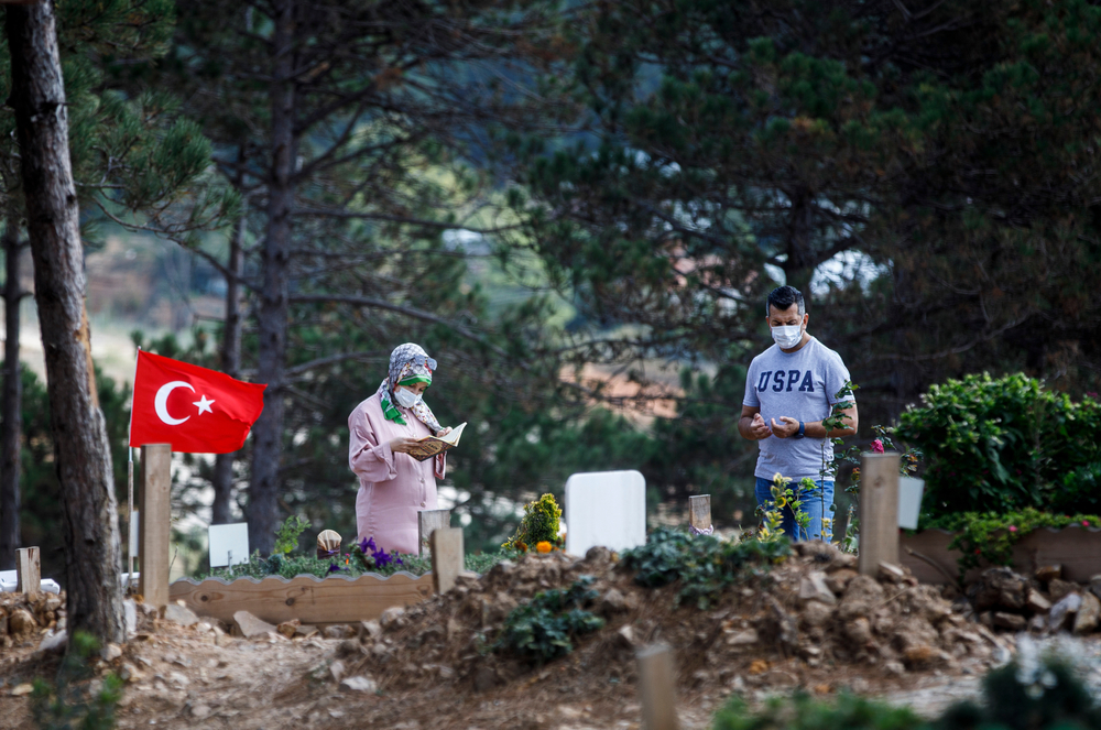 Parenti di una vittima per Covid-19 in un cimitero di Istanbul (© Huseyin Aldemir/Shutterstock)