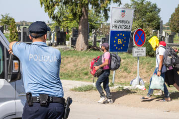 Poliziotto osserva il passaggio di migranti al punto di frontiera croato © BalkansCat/Shutterstock