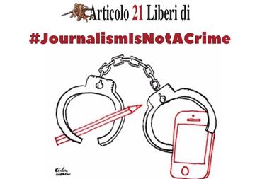 L'immagine raffigura un paio di manette che simbolicamente chiudono una matita e un telefono cellulare. Una frase sopra il disegno dice journalism is not a crime L'immagine raffigura un paio di manette che simbolicamente chiudono una matita e un telefono cellulare. Una frase sopra il disegno dice journalism is not a crime