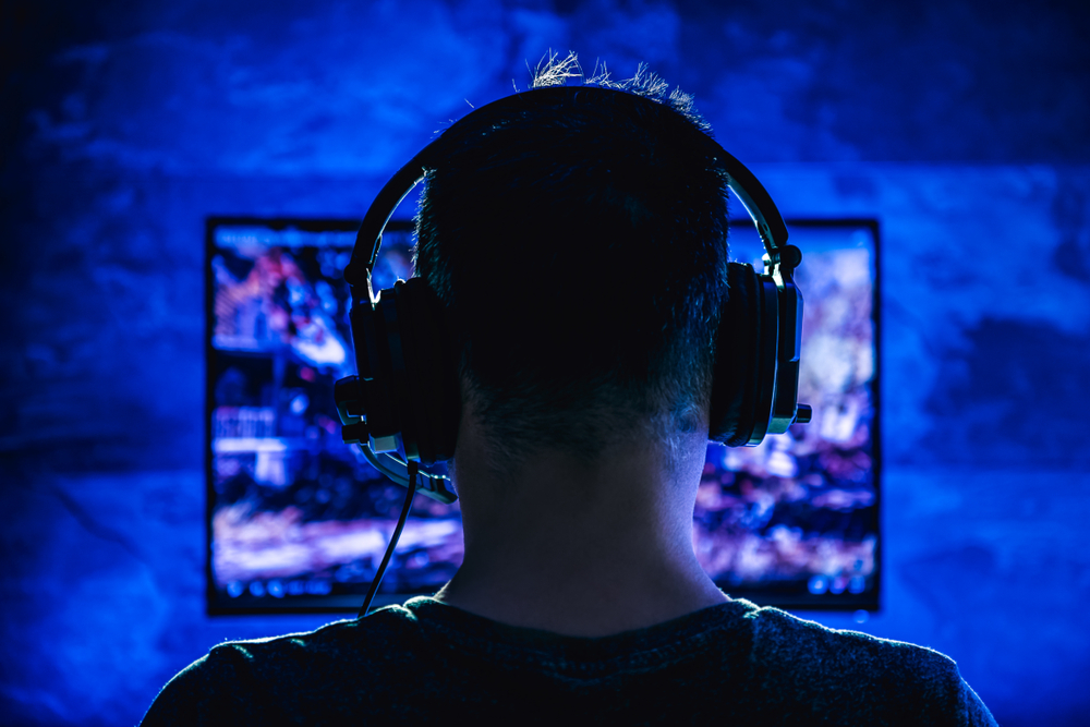 Uomo di spalle con le cuffie mentre gioca ad un videogame © Zivica Kerkez/Shutterstock