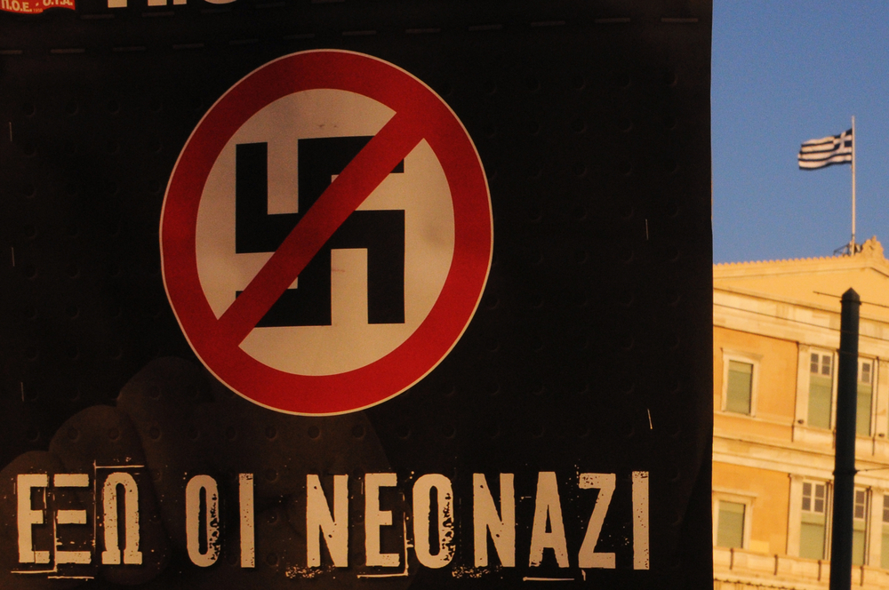 Un cartello con una svastica e il segno di divieto, con scritto "Via i nuovi nazi"(© Kostas Koutsaftikis/Shutterstock)