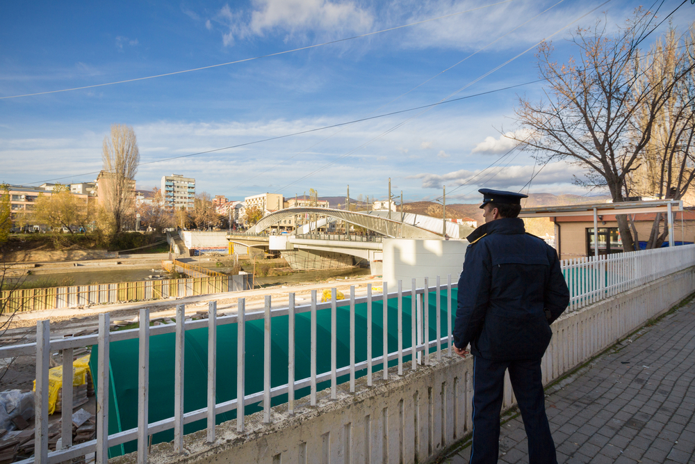 Un poliziotto osserva il ponte sul fiume Ibar che separa la città di Mitrovica nella parte serba e albanese © BalkansCat/Shutterstock