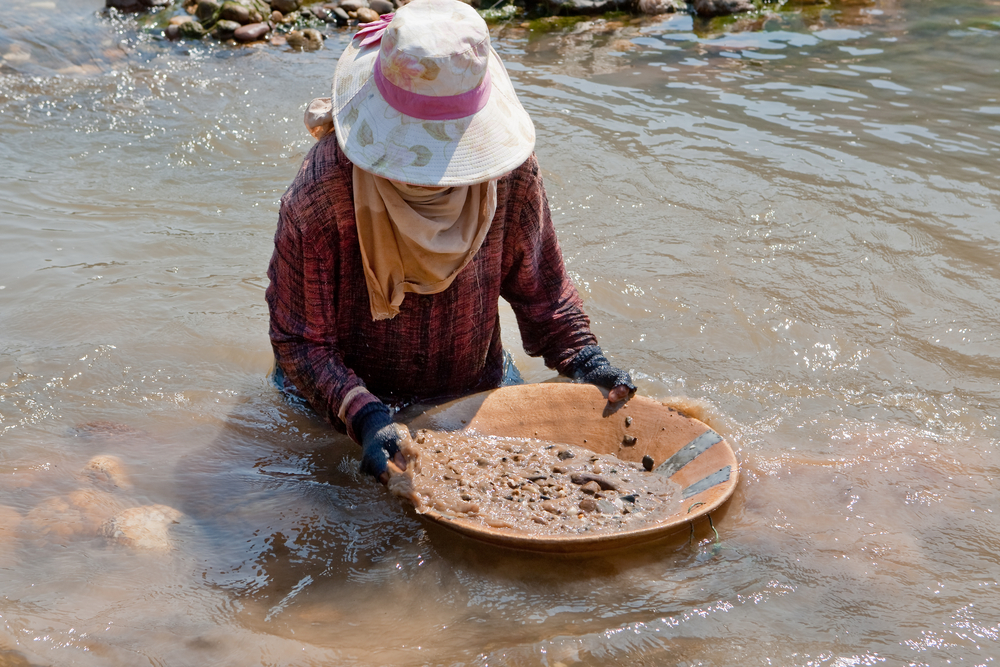 Una donna setaccia la sabbia del fiume in cerca di oro (foto © Muellek Josef/Shutterstock)