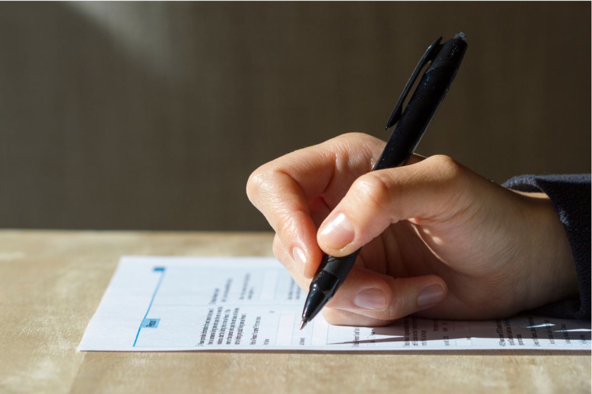 Closeup of woman's hand holding a pen filling out a census form - © Tada Images/Shutterstock