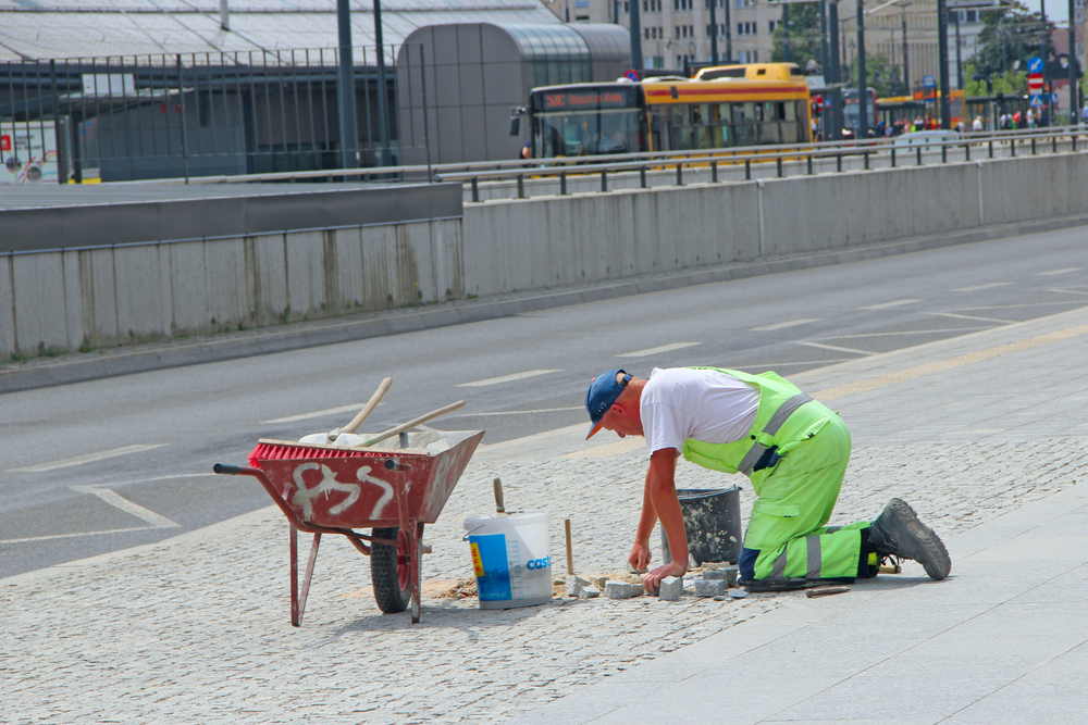 Un lavoratore intento a riparare un marciapiede in Polonia (© alexmak7/Shutterstock)