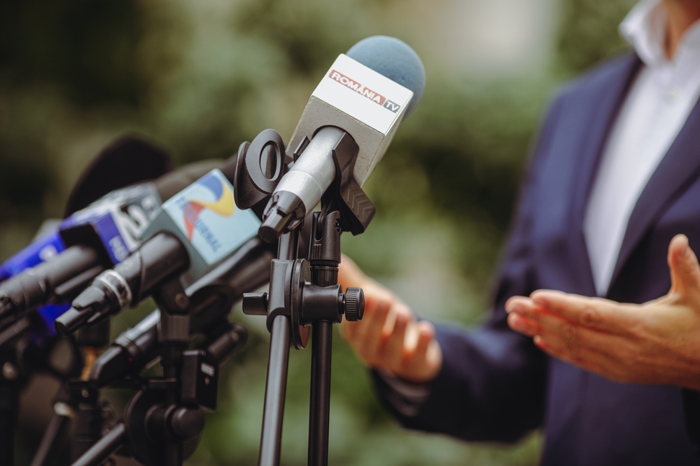 Durante una conferenza stampa in Romania, microfoni in primo piano, figura sfocata sul retro - Mircea Moira/Shutterstock