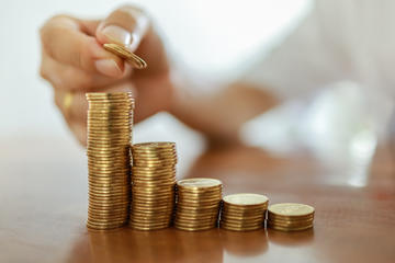 Una mano impila delle monete di metallo (© Montri Thipsorn/Shutterstock)