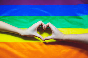 Bandiera arcobaleno e due mani che formano un cuore © Only_NewPhoto/Shutterstock