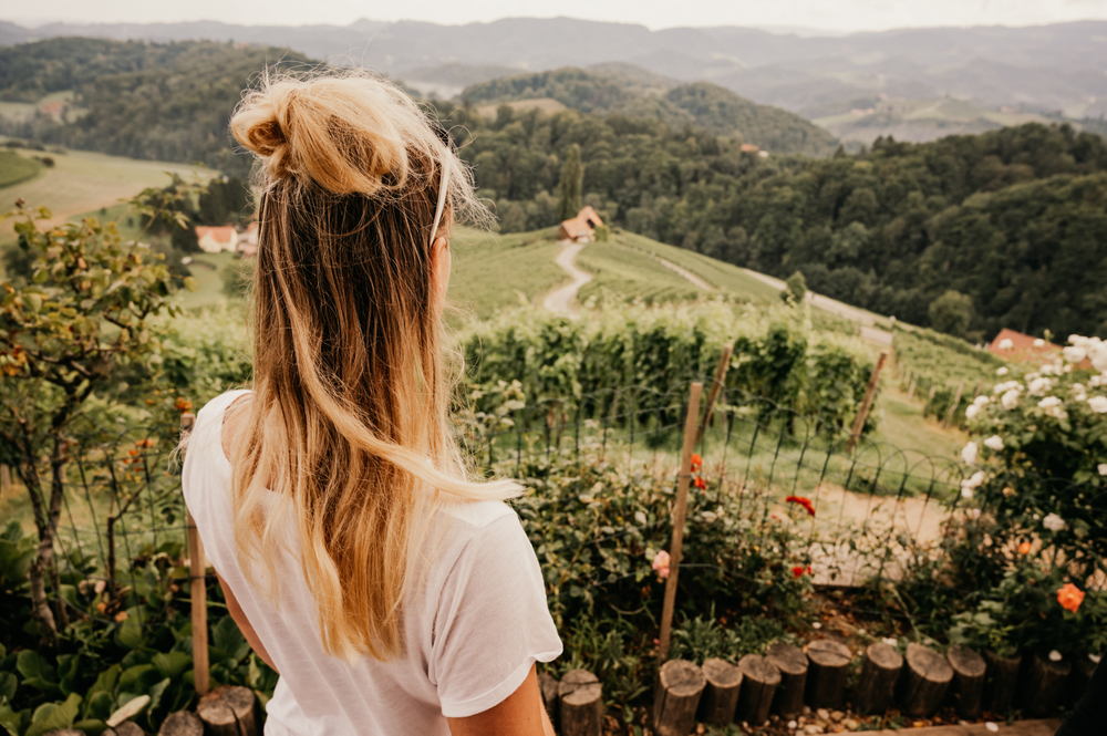 Donna di spalle e davanti a lei un paesaggio di mezza montagna in Slovenia