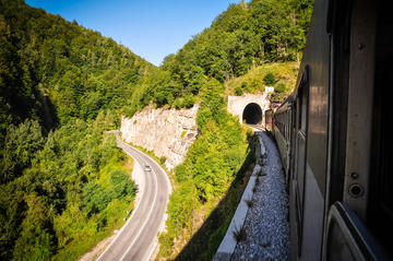 train entering a tunnel next to a road