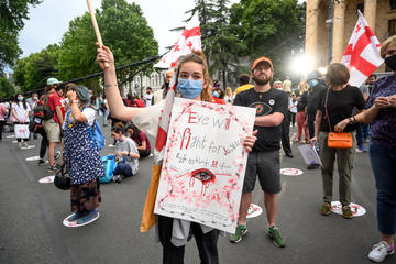 Una ragazza manifesta con la mascherina per il covid19 davanti al parlamento georgiano