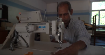 Un fotogramma del video raffigurante un migrante davanti alla macchina da cucire