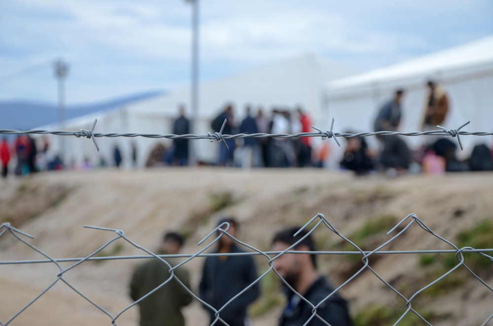 Migrants behind barbed wire in a camp © Ajdin Kamber/Shutterstock