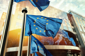 Bandiere dell’UE sventolano davanti al palazzo del Parlamento europeo © symbiot/Shutterstock