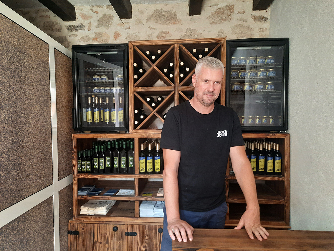 Il pescatore Krsto Ivoš con dietro l’olio d’oliva e altre casette di produzione familiare - Foto G. Vale