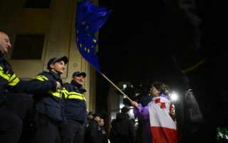 Dimostrante sventola in faccia alla polizia la bandiera dell'UE, Tbilisi, Georgia, 2025 © Gela Bedianashvili/Shutterstock