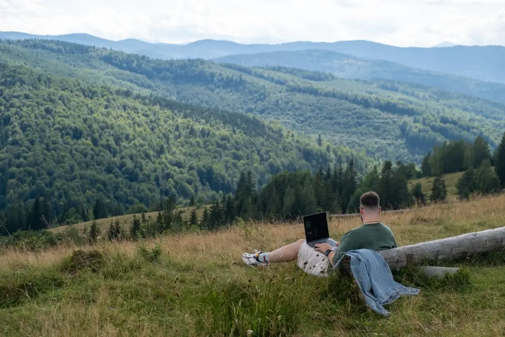 Un giovane lavorando a remoto in un’area montana – © Vera Petrunina/Shutterstock Un giovane lavorando a remoto in un’area montana - © Vera Petrunina/Shutterstock